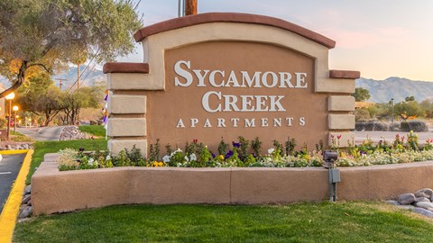 a sign apartments in front of a flower garden